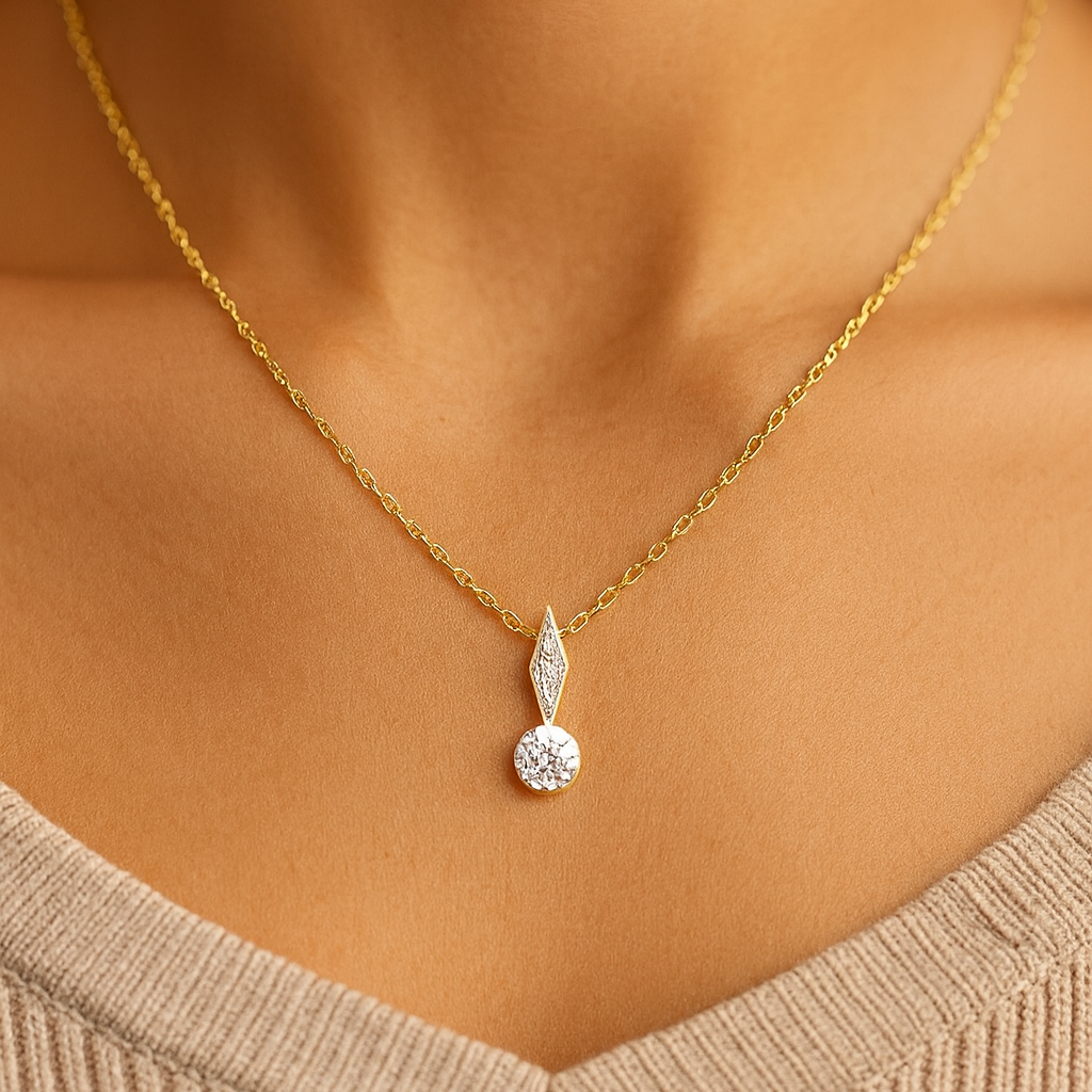 Gold necklace with a diamond pendant on a person wearing a beige sweater.