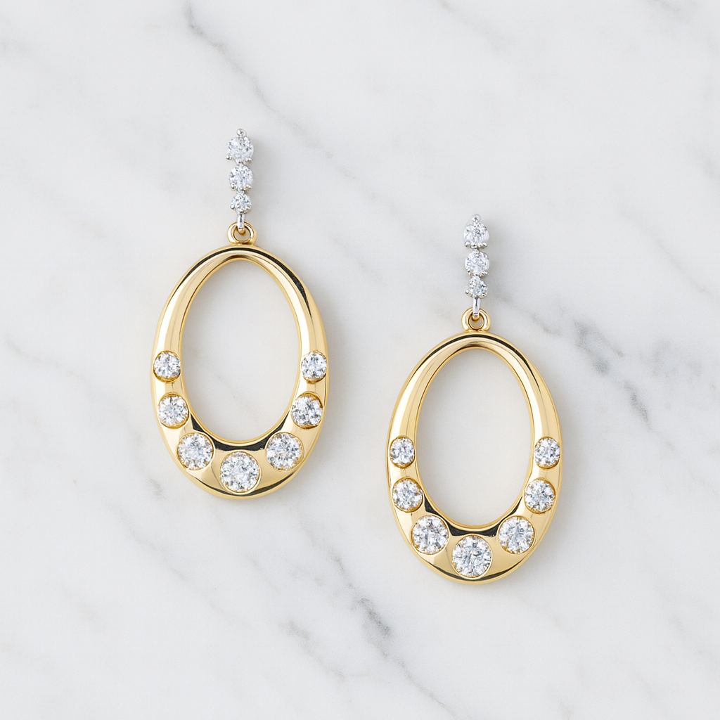 Gold hoop earrings with clear gemstones on a marble background