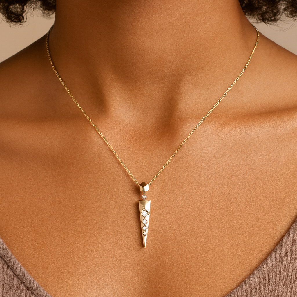 Gold necklace with a pendant on a person wearing a brown top