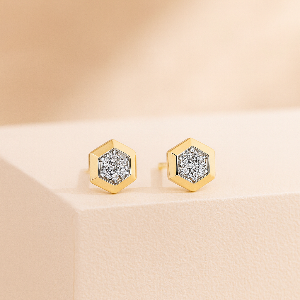 Gold hexagonal earrings with diamond-like inserts on a beige background