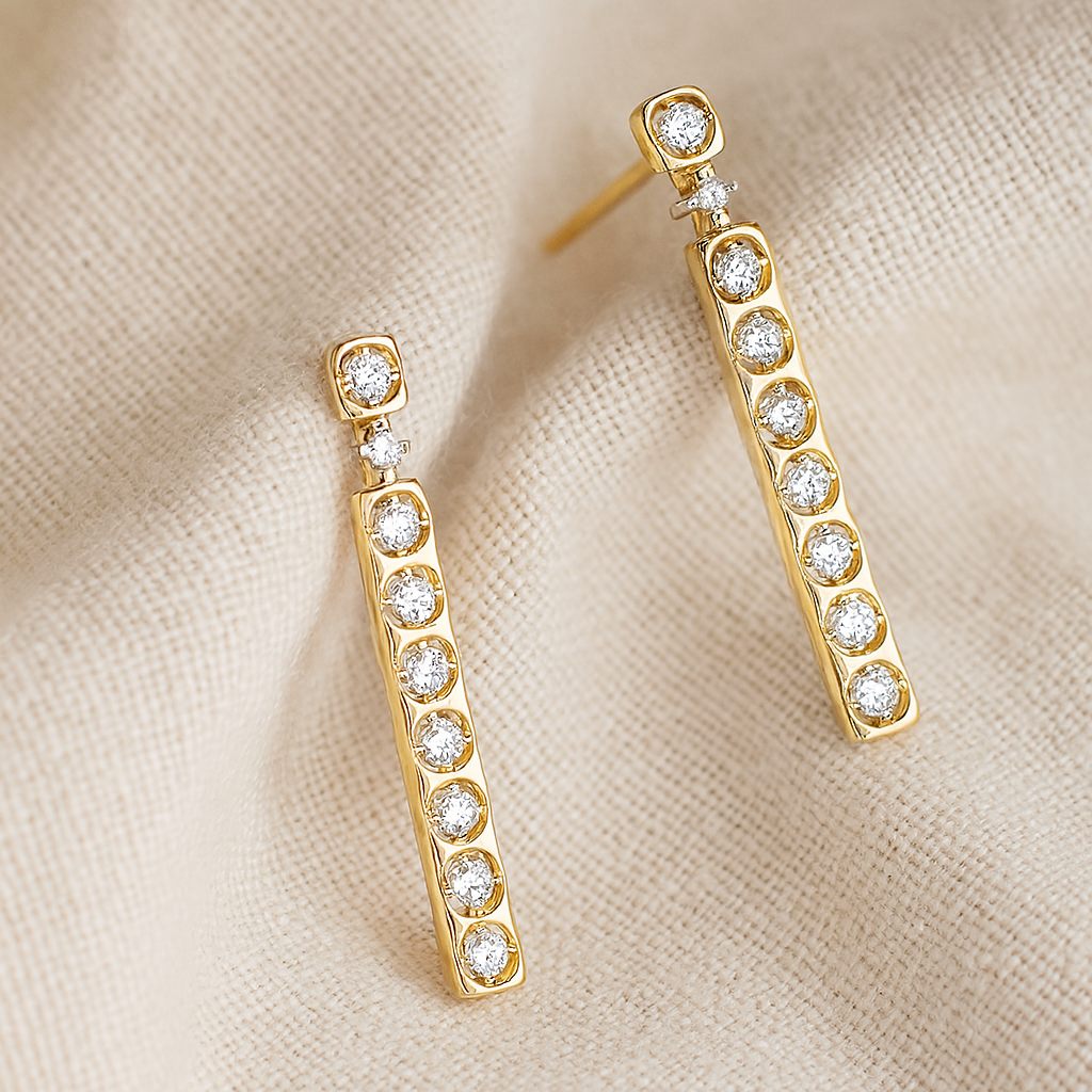 Gold earrings with clear stones on a beige fabric background