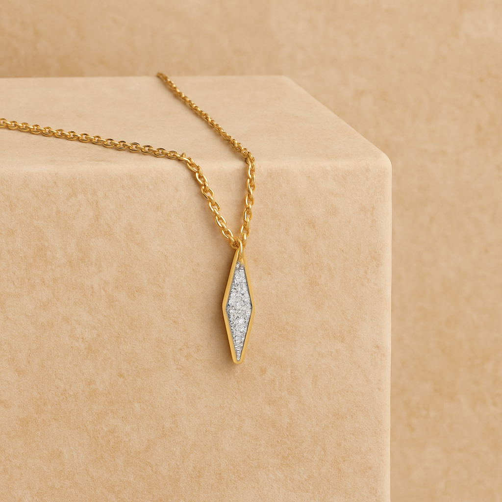 Gold necklace with a diamond-shaped pendant on a beige surface
