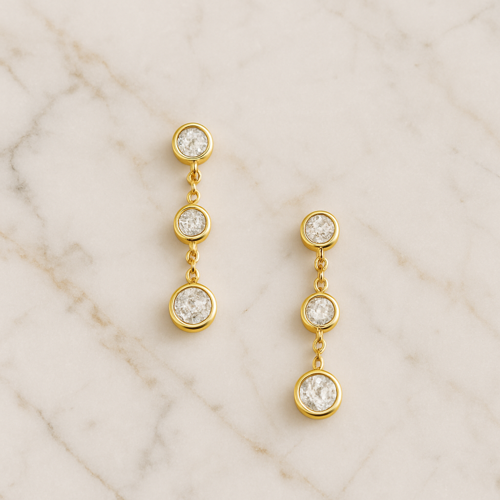 Gold earrings with white sapphires placed on a marble background