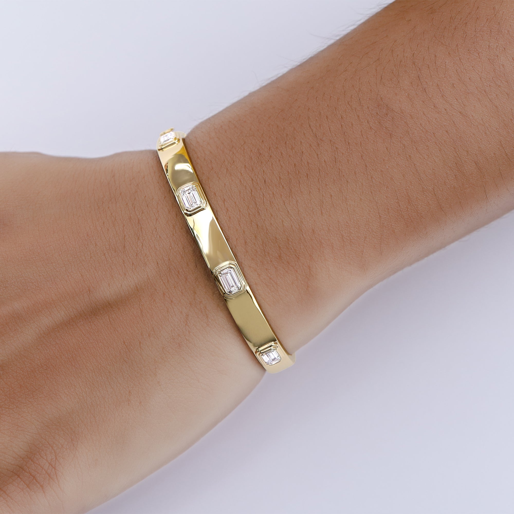 Gold bracelet with diamond accents on a wrist against a white background