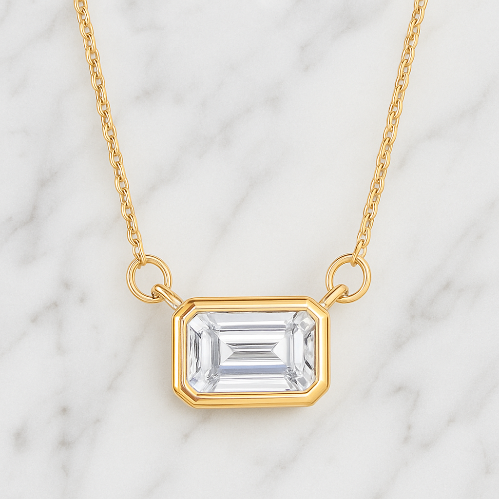 Gold necklace with a clear gemstone pendant on a marble background