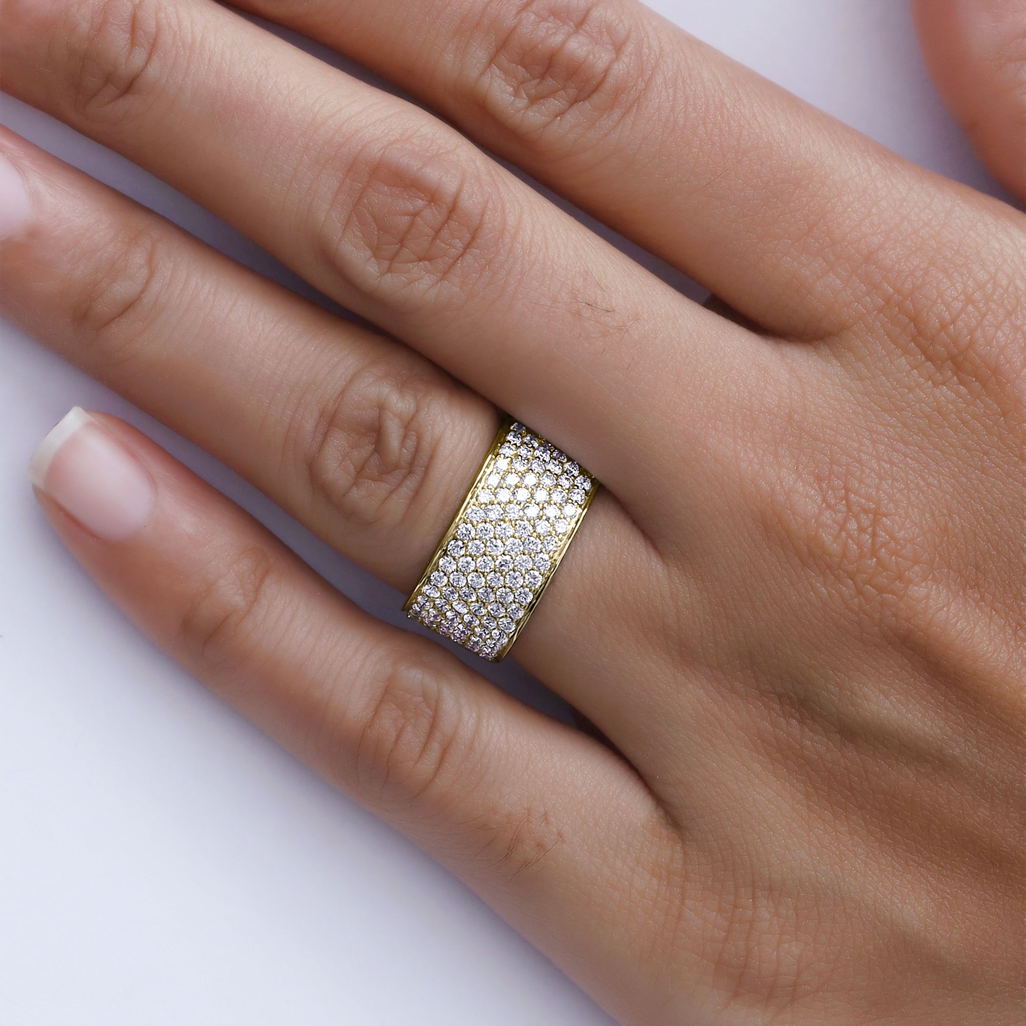 Close-up of a hand wearing a gold and diamond ring on a white background