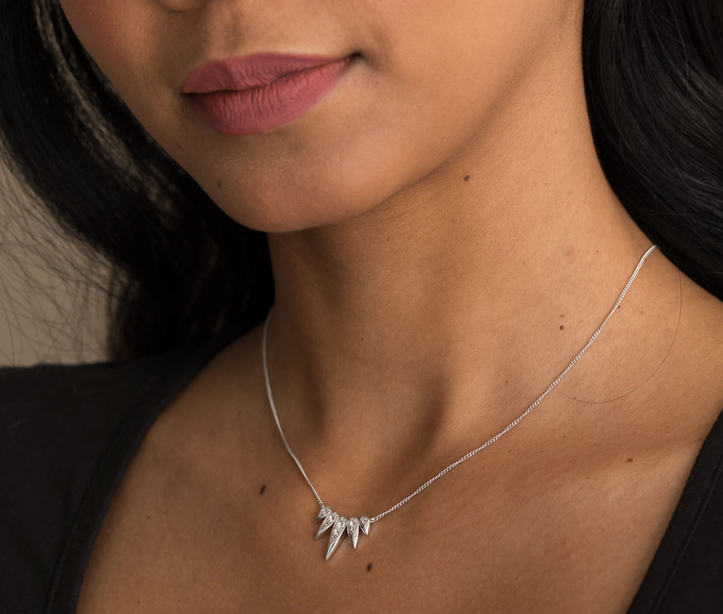 Sterling silver necklace with a pointed gemstone pendant on a woman's neck.