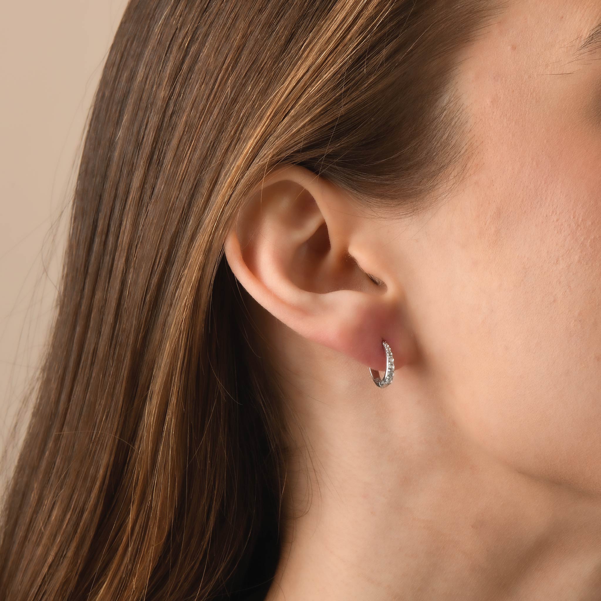 Close-up of ear wearing sterling silver and 14K gold earrings with white sapphires.