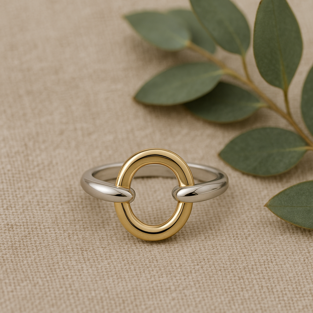 Gold and silver ring on a beige fabric background with green leaves