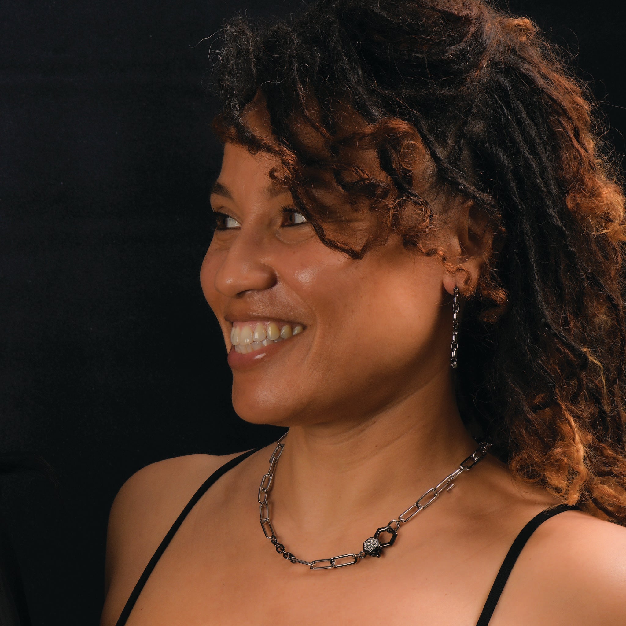 Woman wearing a sterling silver paperclip necklace with black accents and drop earrings.