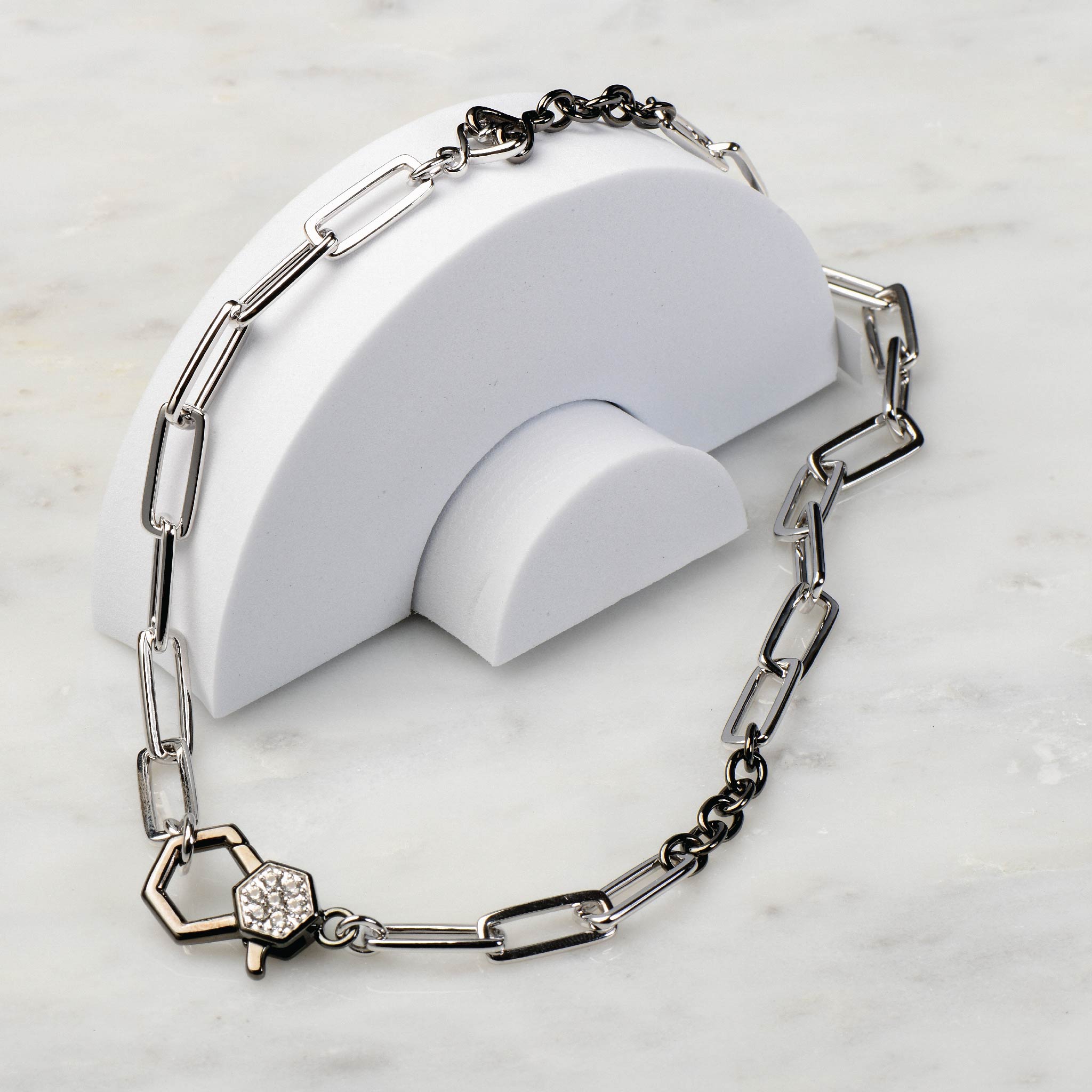 Sterling silver and black paperclip necklace with white sapphire detail on marble surface.