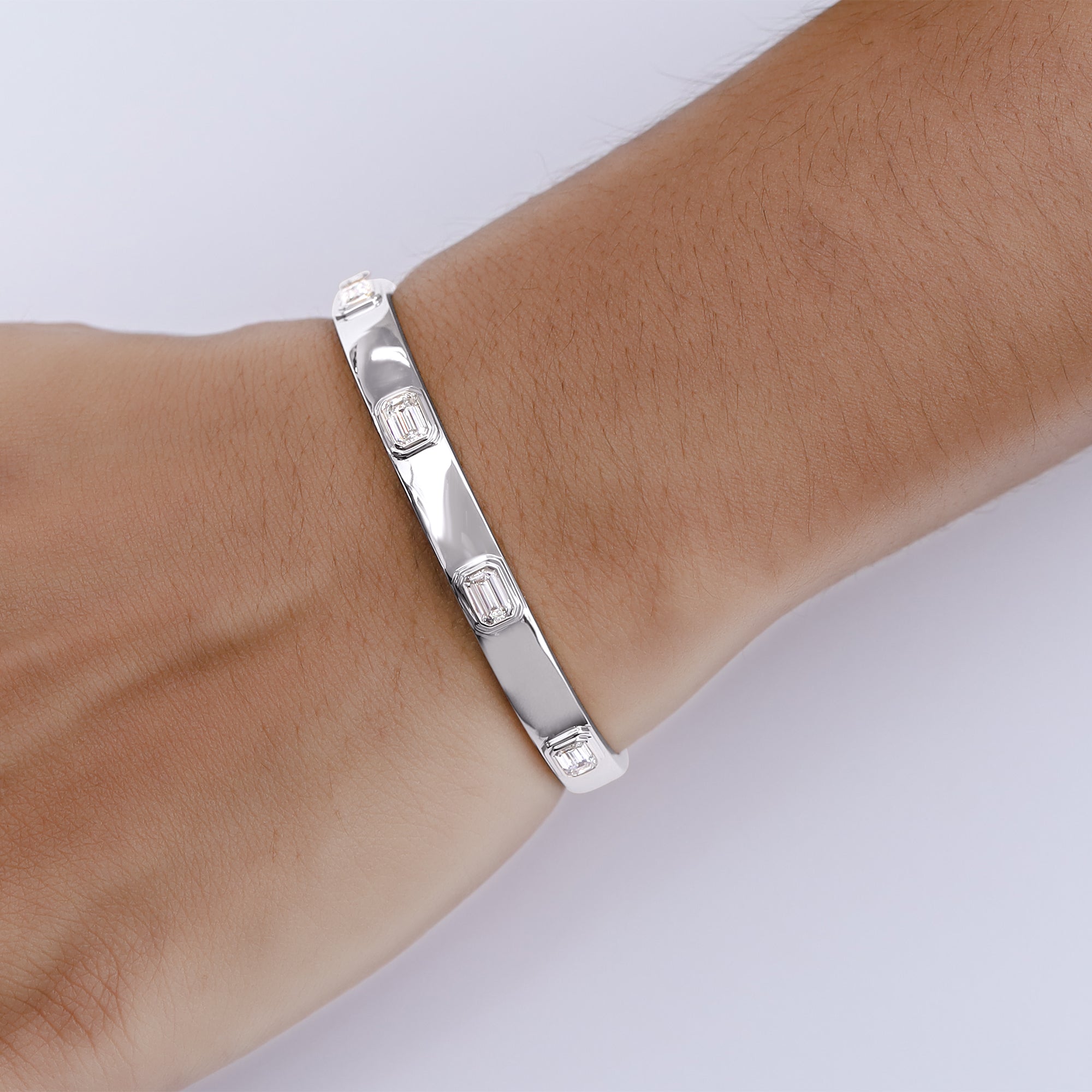 Silver bracelet on a wrist with a plain background