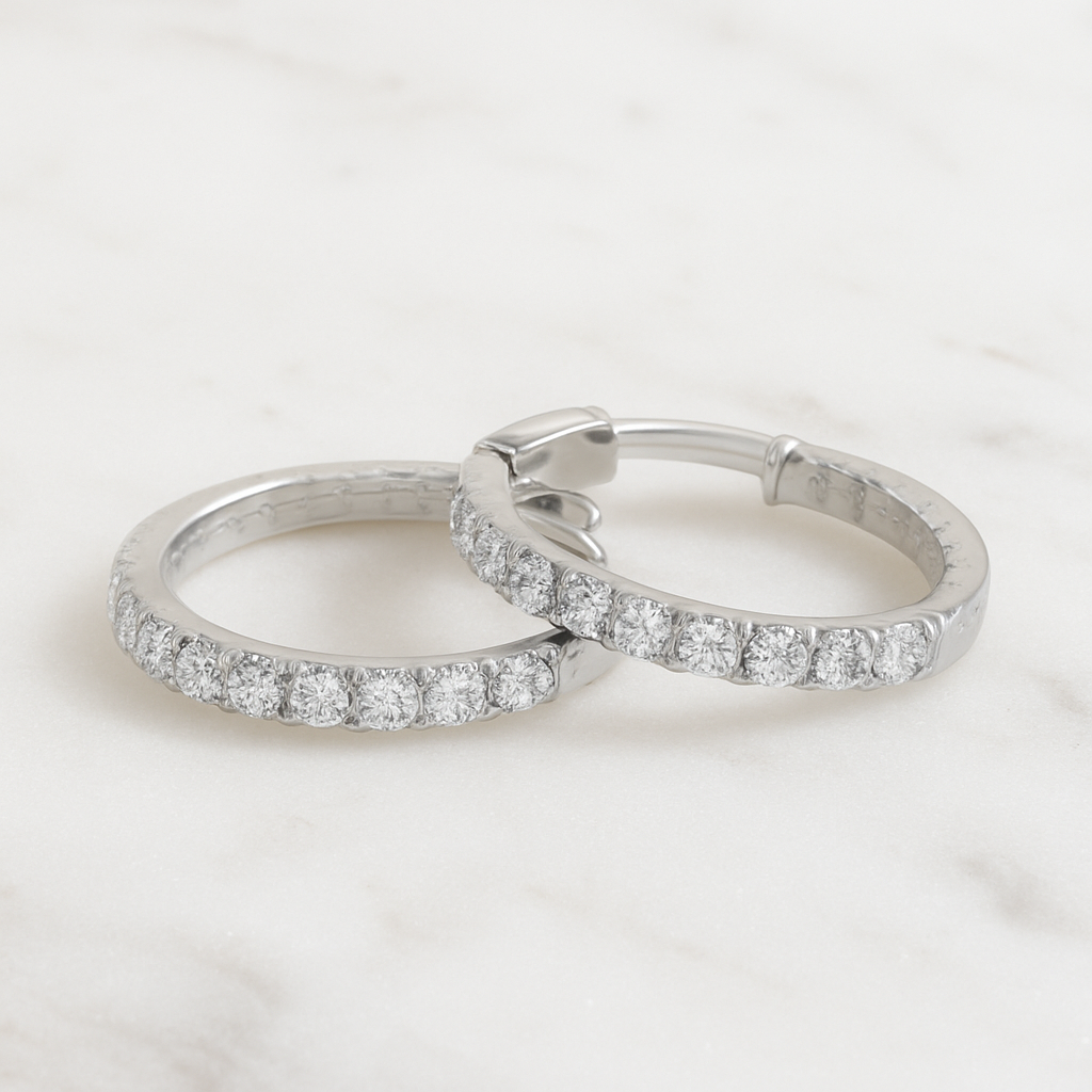 Pair of silver hoop earrings with clear gemstones on a light gray background