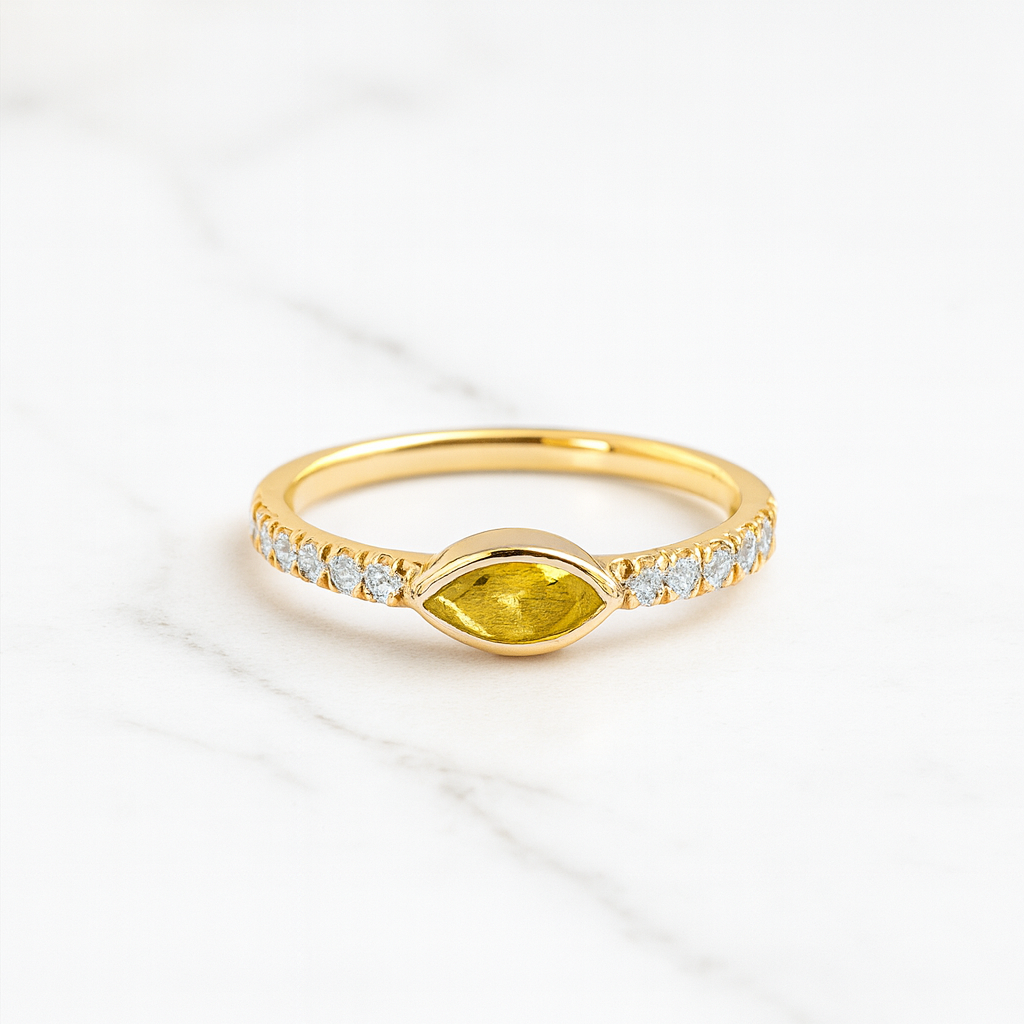 Gold ring with a yellow gemstone and diamond accents on a white background