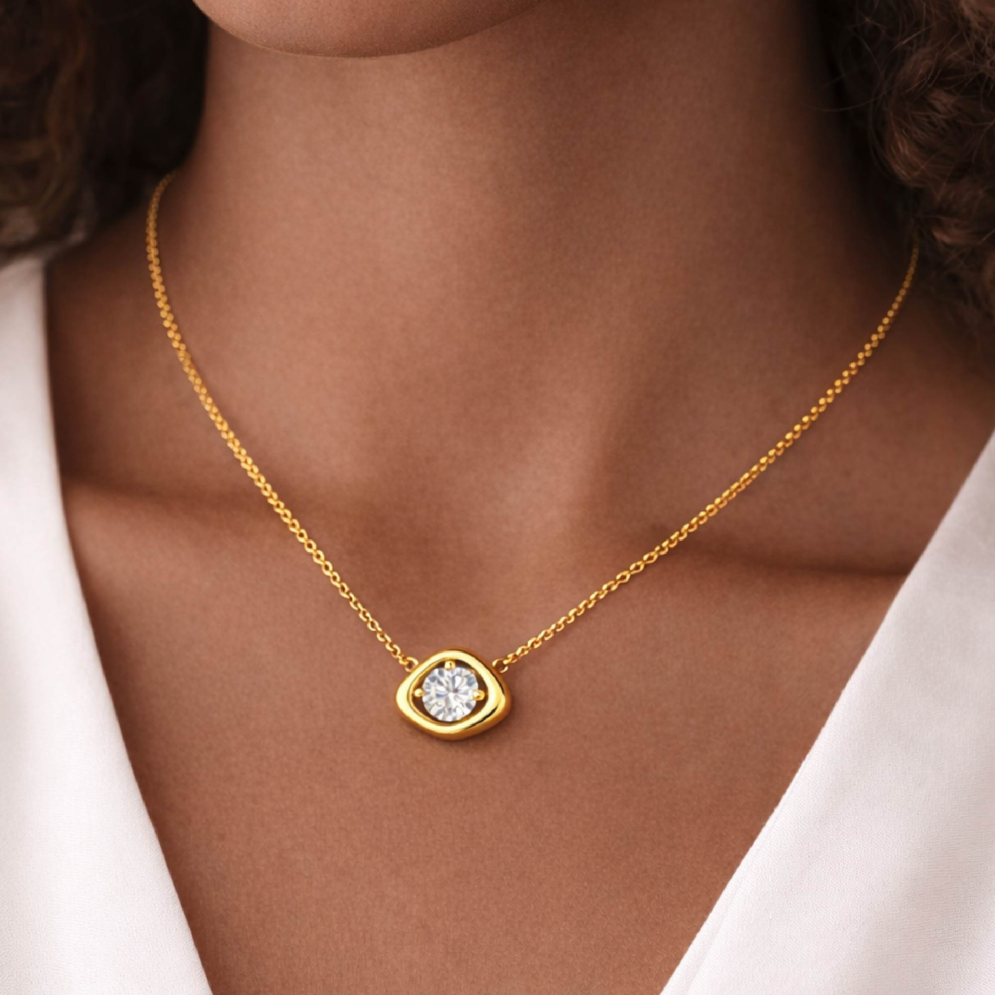 Gold necklace with a heart-shaped pendant worn by a person