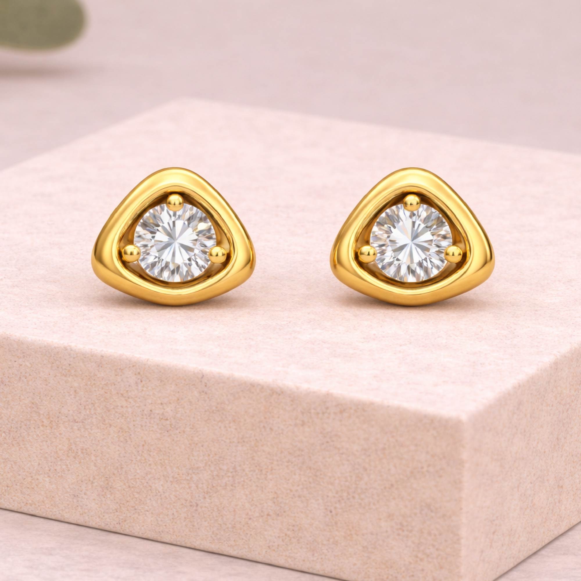 Gold earrings with clear gemstones on a pink box