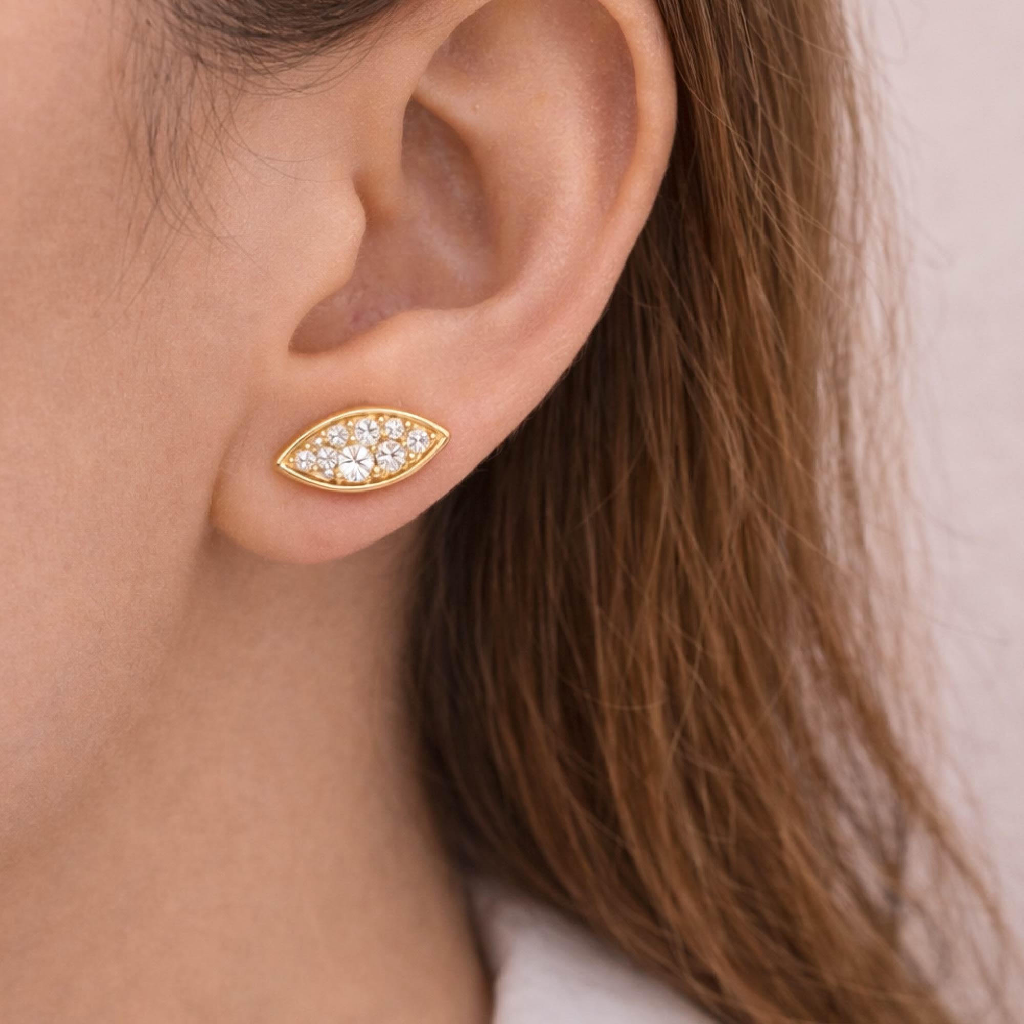 Gold earring with clear stones worn by a person