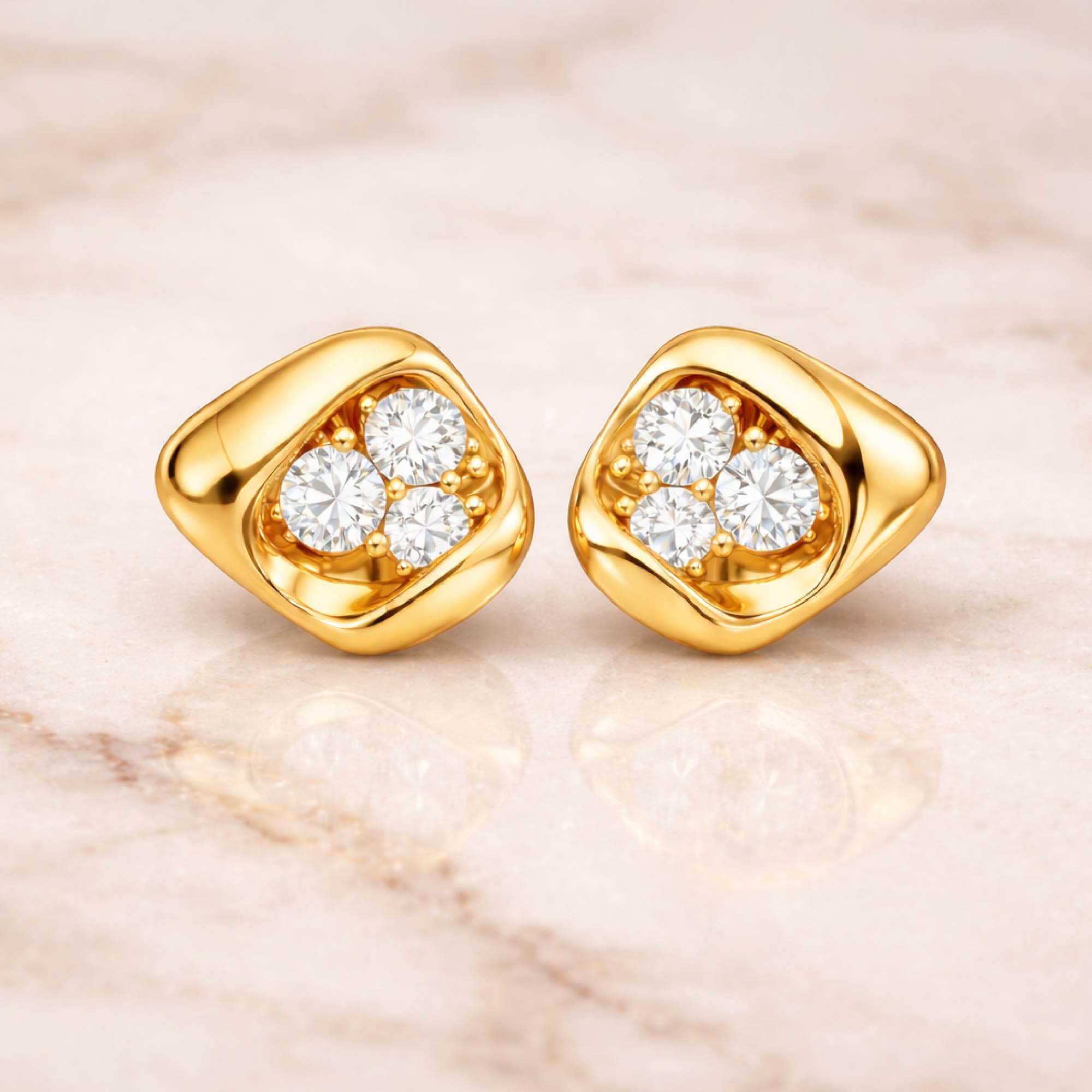 Gold earrings with diamond-like stones on a marble surface