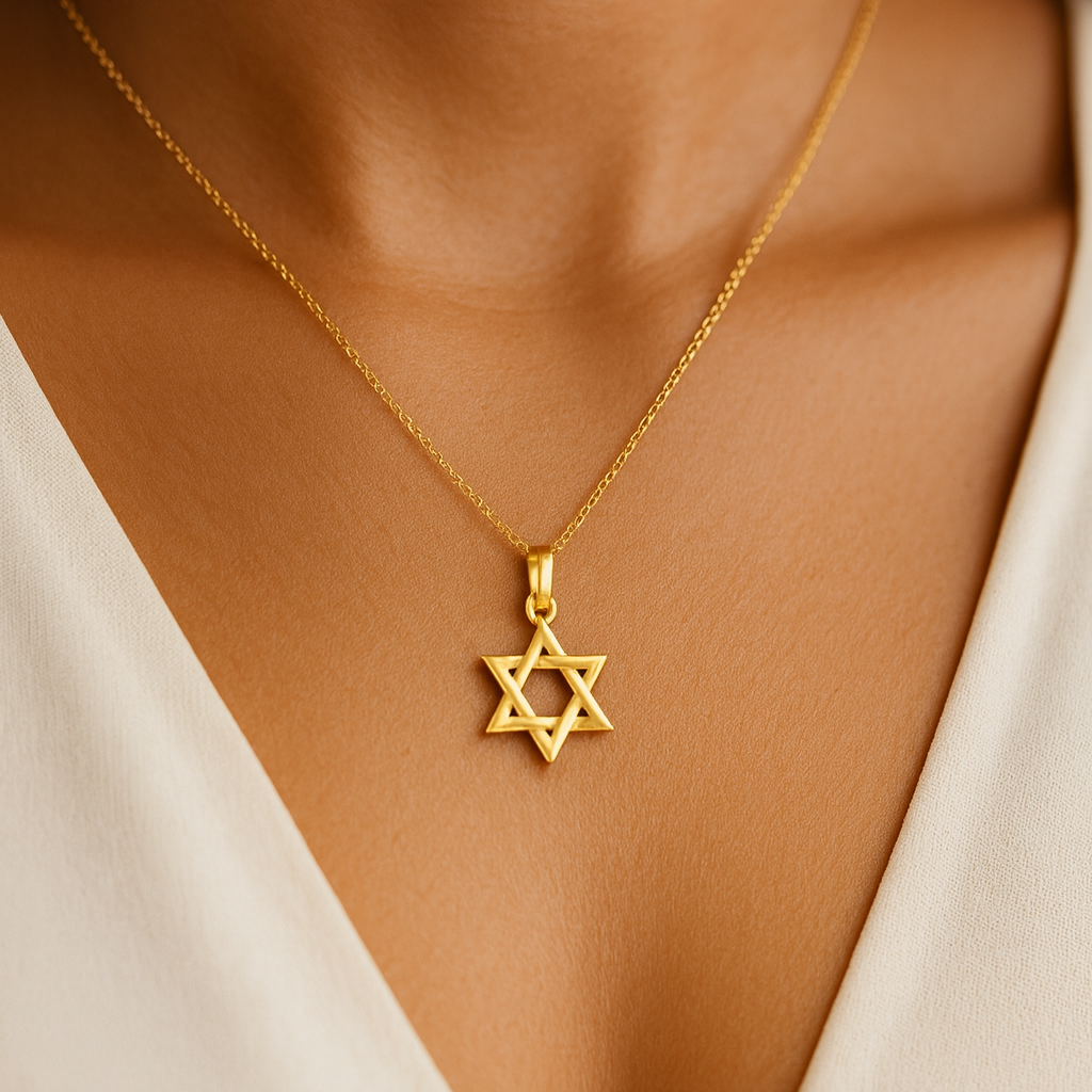 Gold necklace with a Star of David pendant on a person wearing a white top.