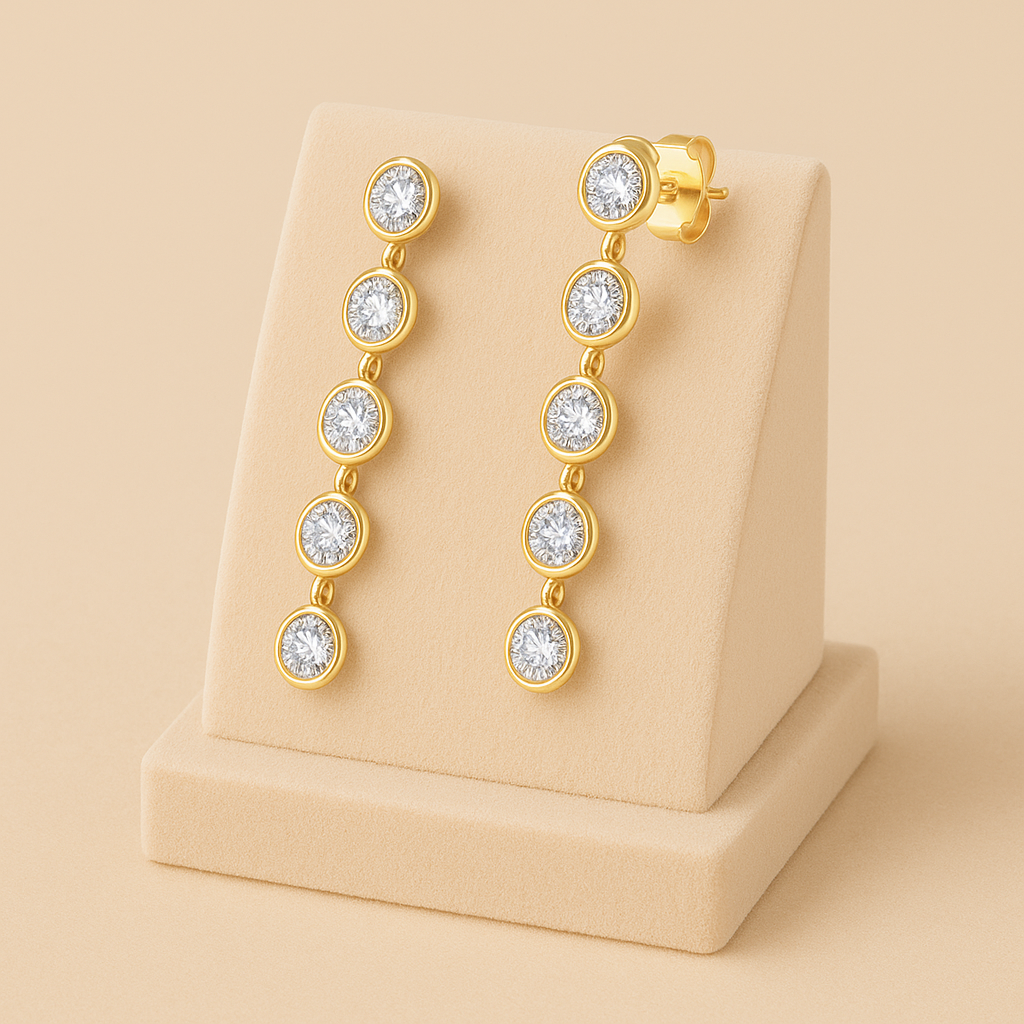 Gold earrings with clear stones on a beige stand