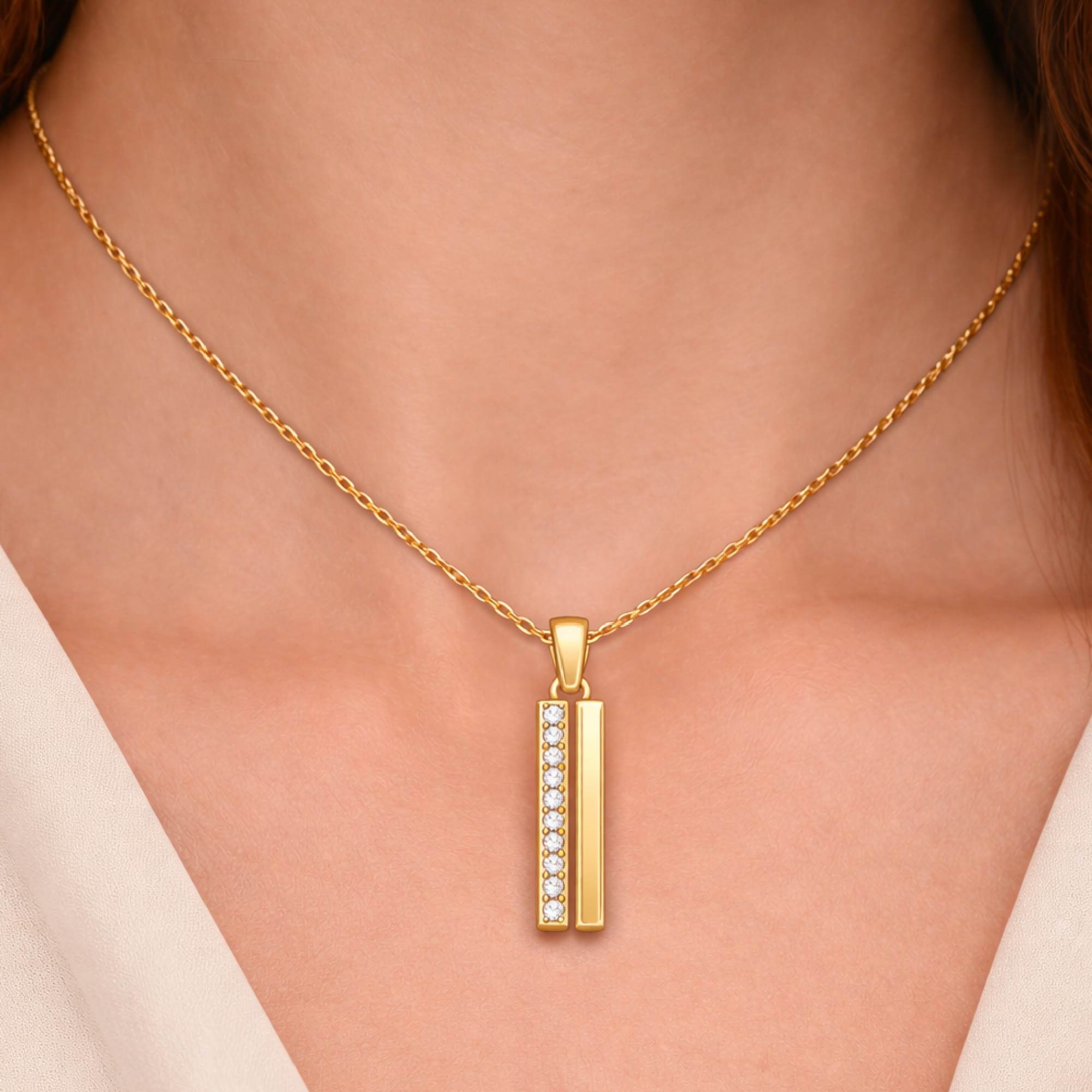 Gold necklace with a pendant on a person wearing a beige top