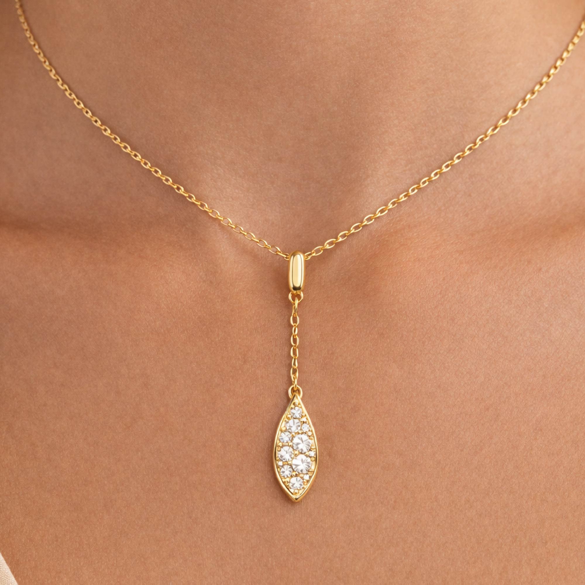 Gold necklace with a teardrop-shaped pendant on a person's neck