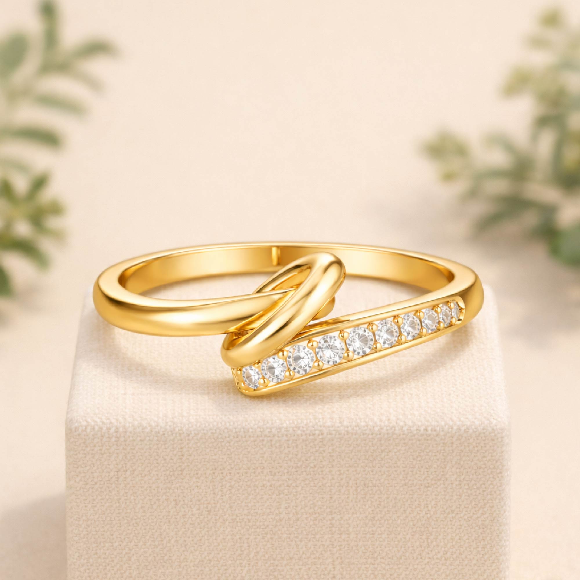 Gold ring with diamond accents on a beige surface with blurred greenery