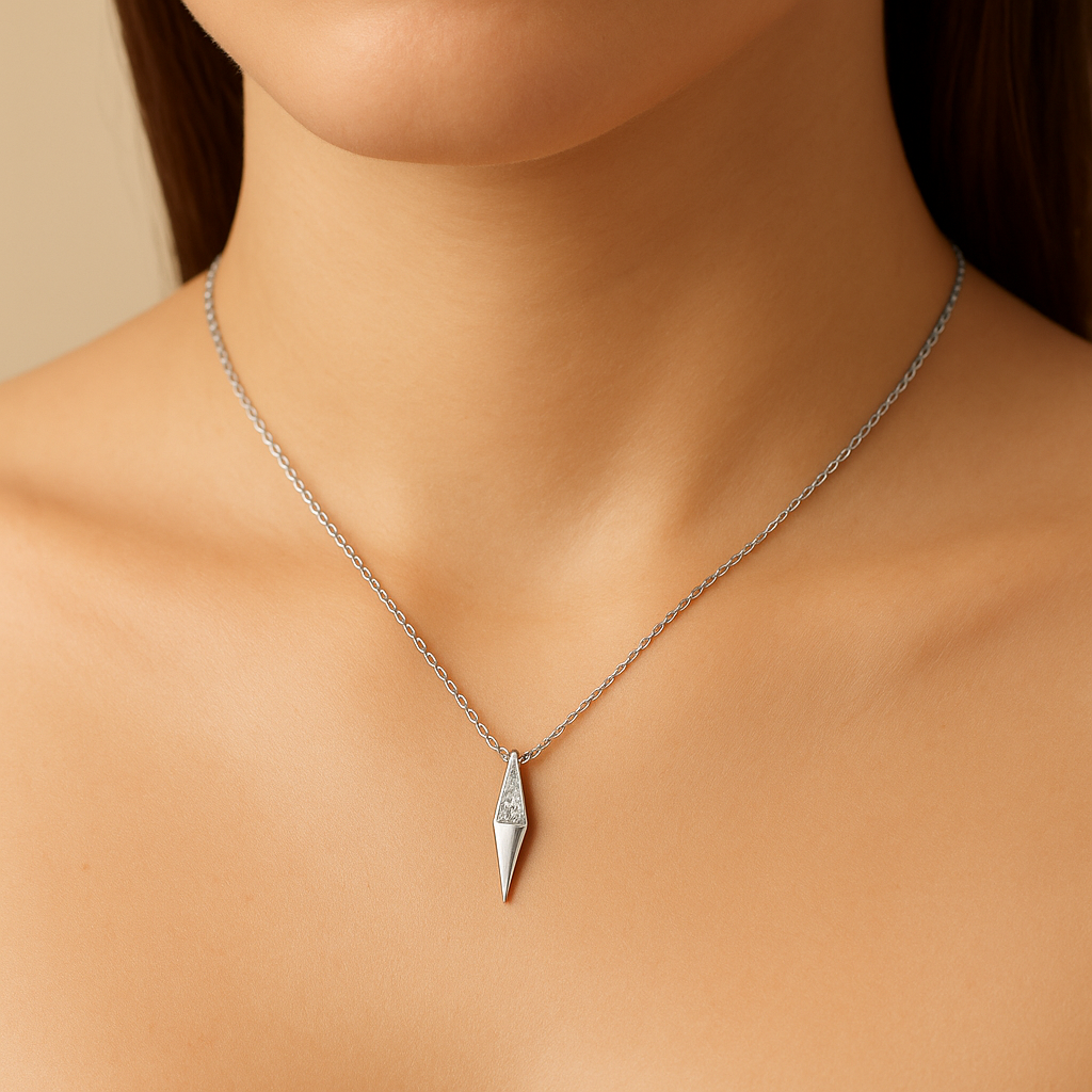 Silver necklace with a pendant on a person's neck against a neutral background