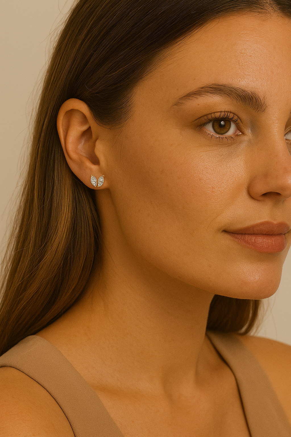 Close-up of a woman wearing diamond earrings with a neutral background