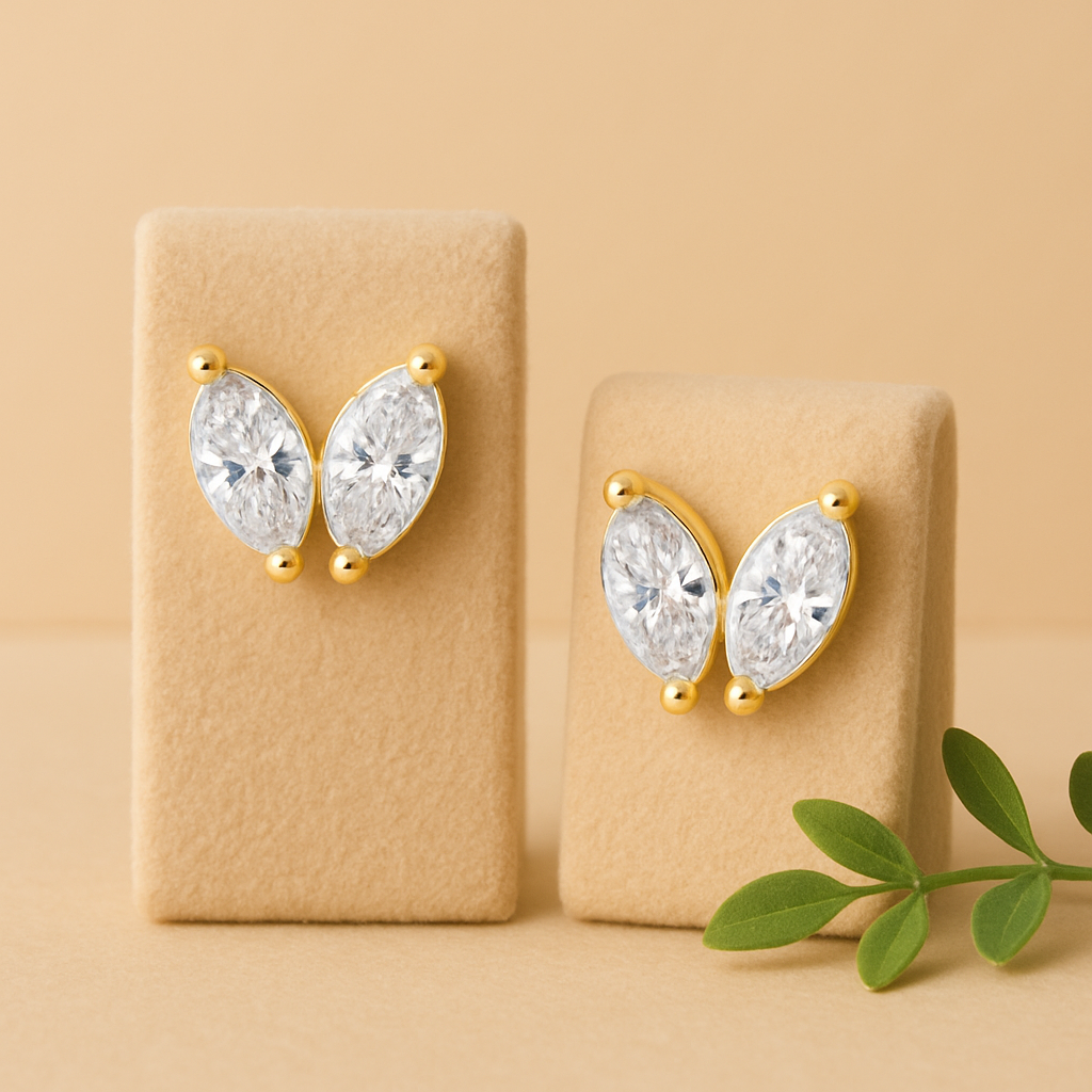 Gold and crystal earrings on beige display stands with a green leaf on a beige background