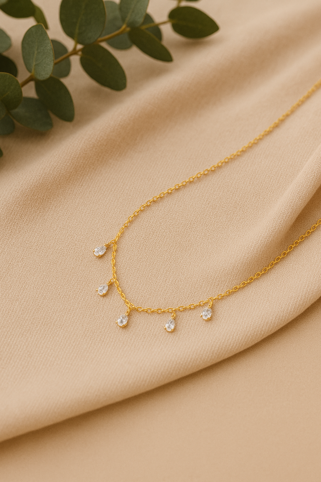 Gold necklace with small stones on a beige fabric background