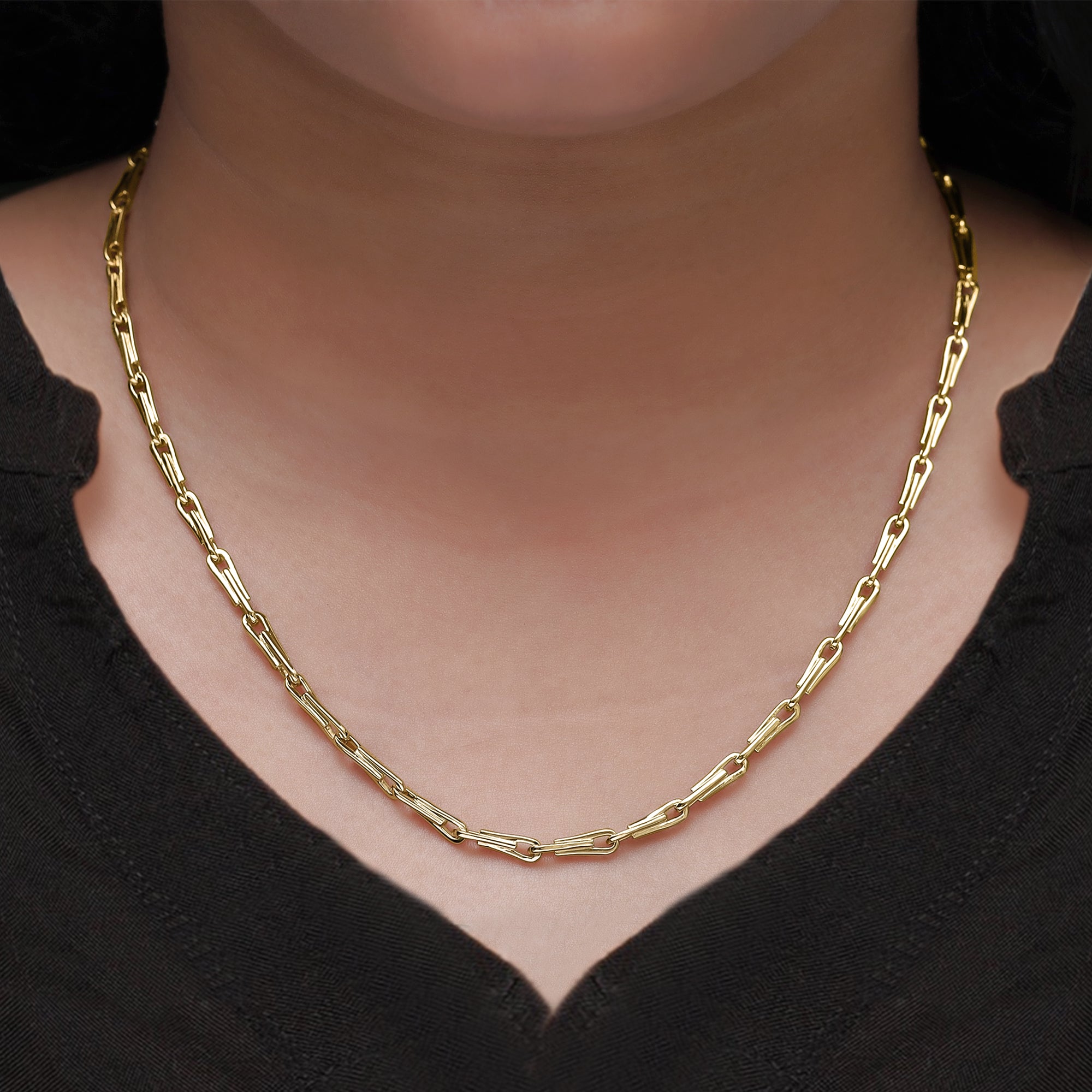 Gold chain necklace on a person wearing a black top