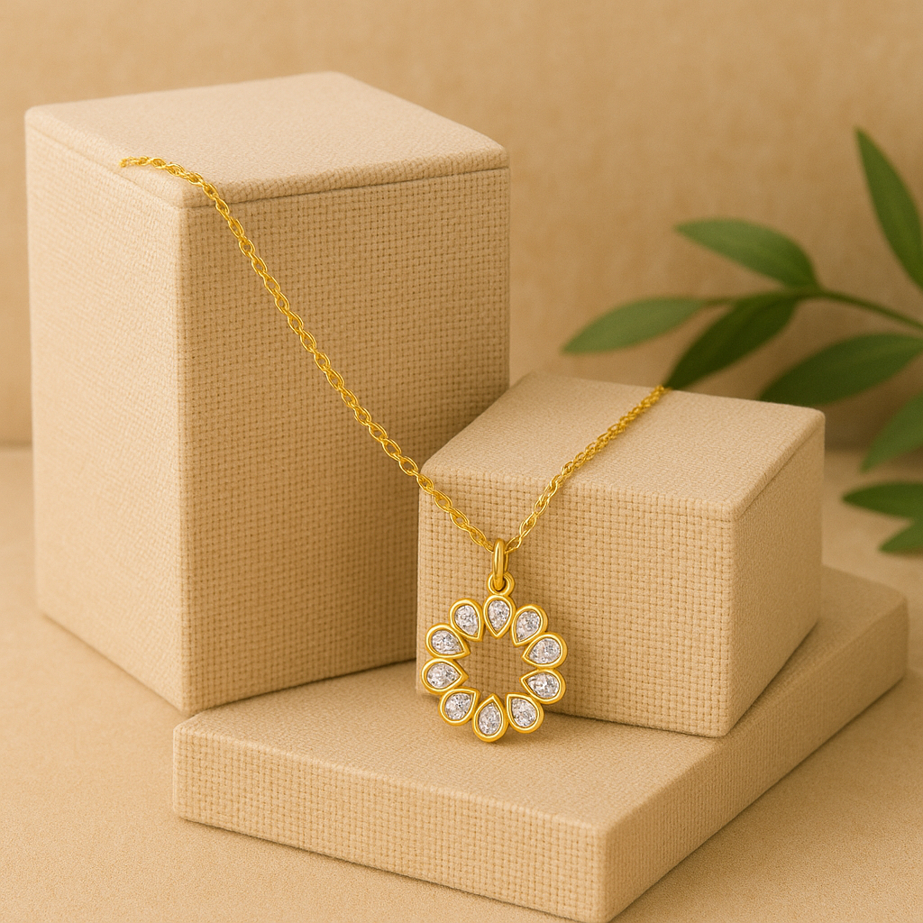 Gold necklace with a floral pendant on a beige box with a plant in the background