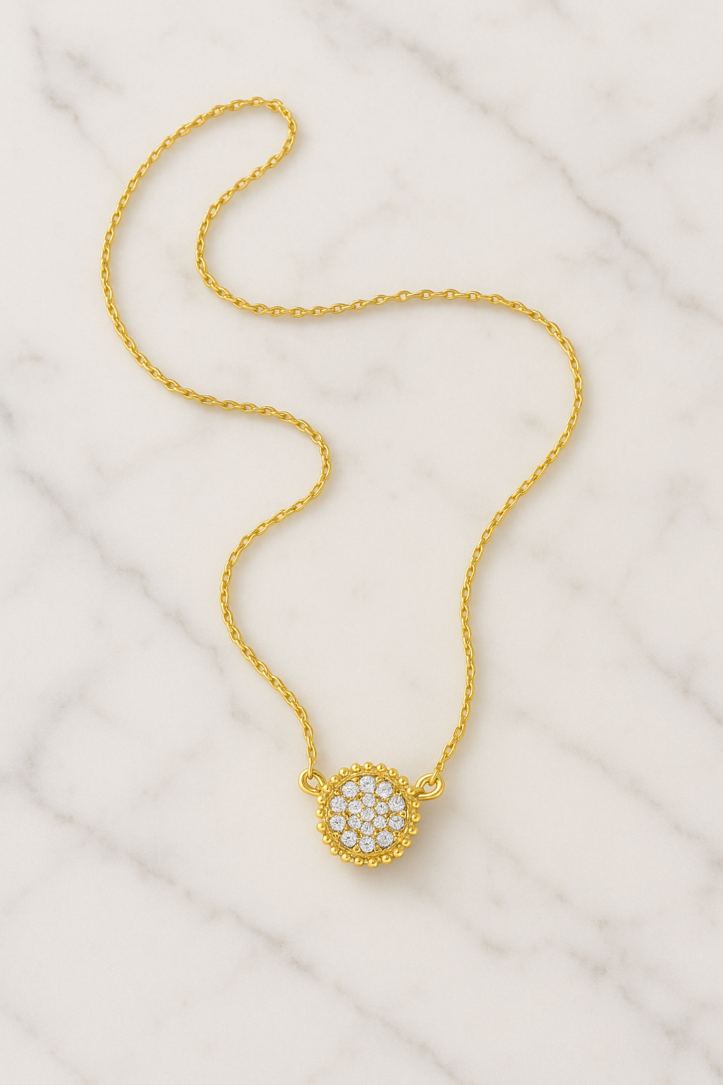 Gold necklace with a circular pendant on a white fabric background