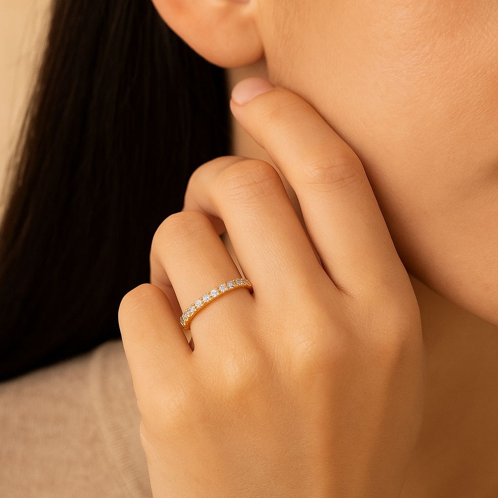 Close-up of a hand wearing a gold ring with diamonds, touching the chin.