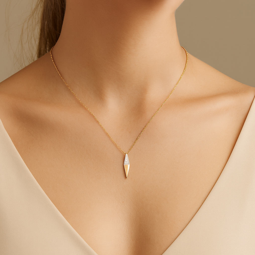 Gold necklace with a triangular pendant on a neutral background