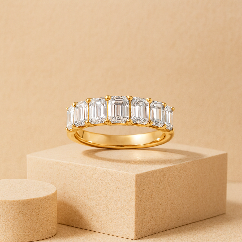 Gold ring with emerald-cut diamonds on a beige background