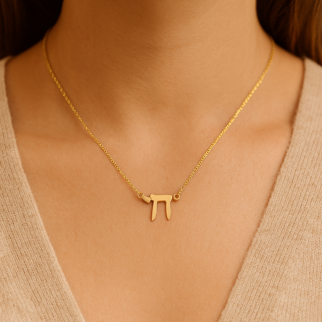 Gold necklace with a unique pendant on a person wearing a beige top.
