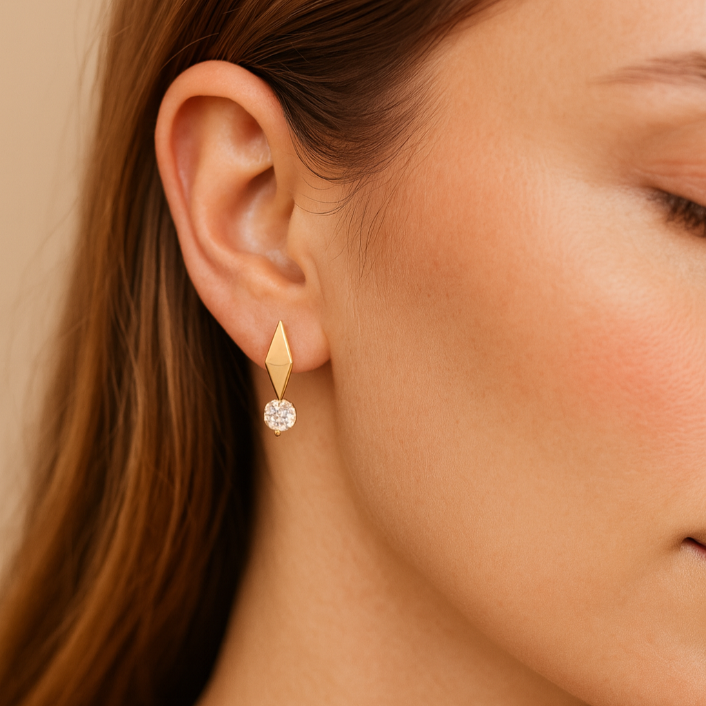 Close-up of a woman wearing a gold earring with a clear gemstone.