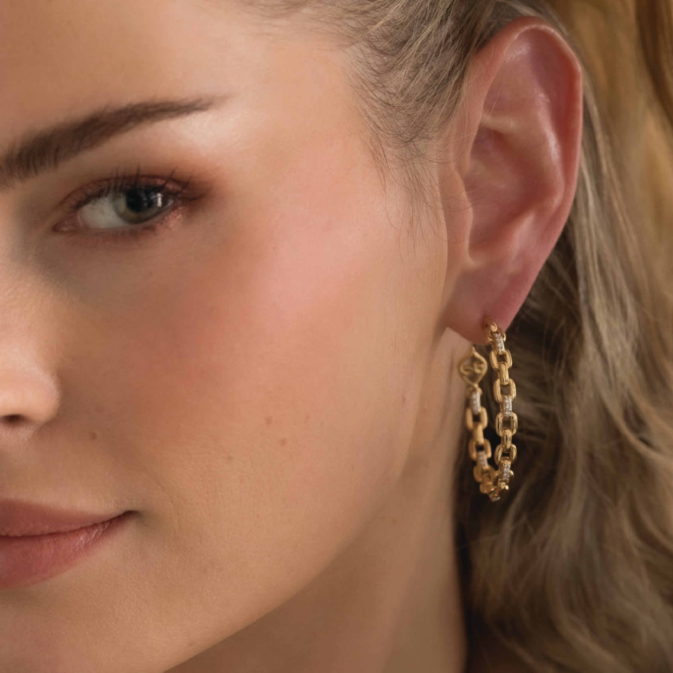 Close-up of woman wearing 14K solid gold hoop earrings with diamonds.
