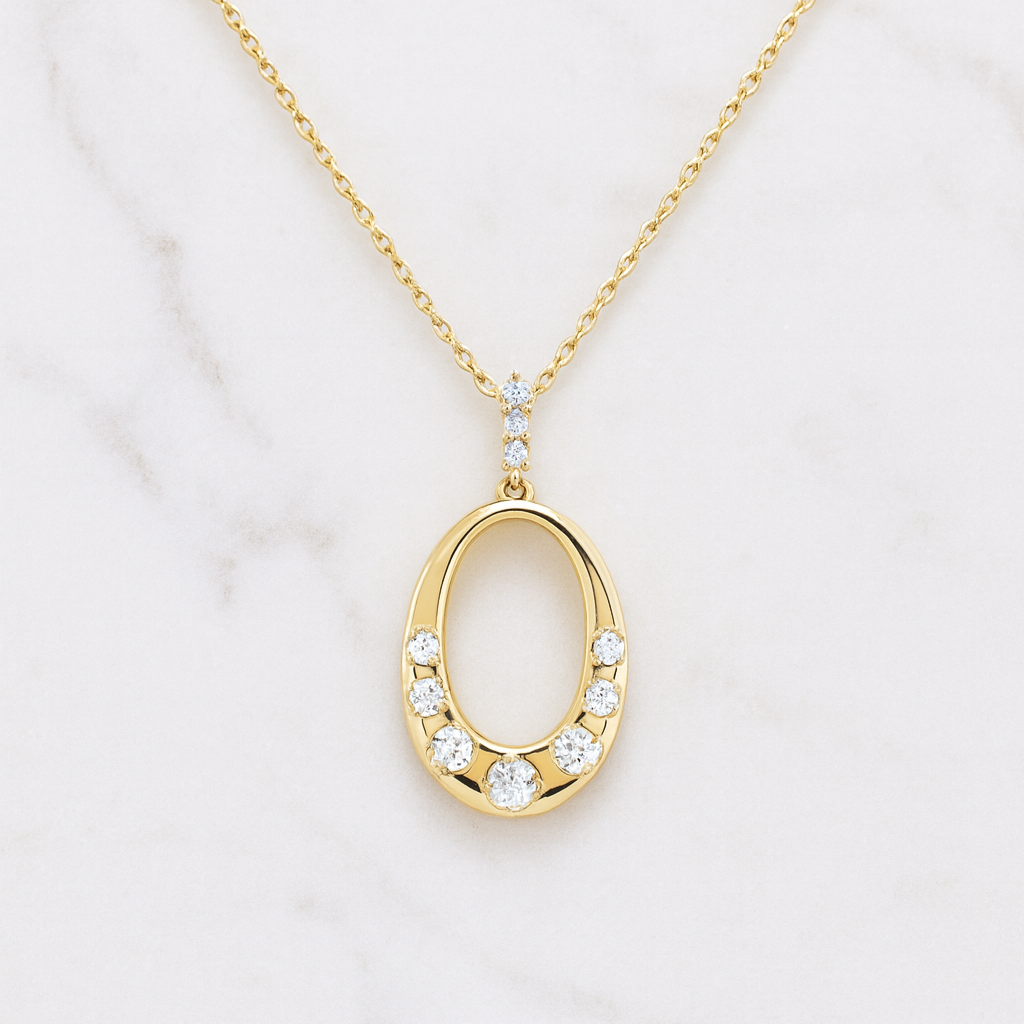 Gold necklace with an oval pendant on a marble background