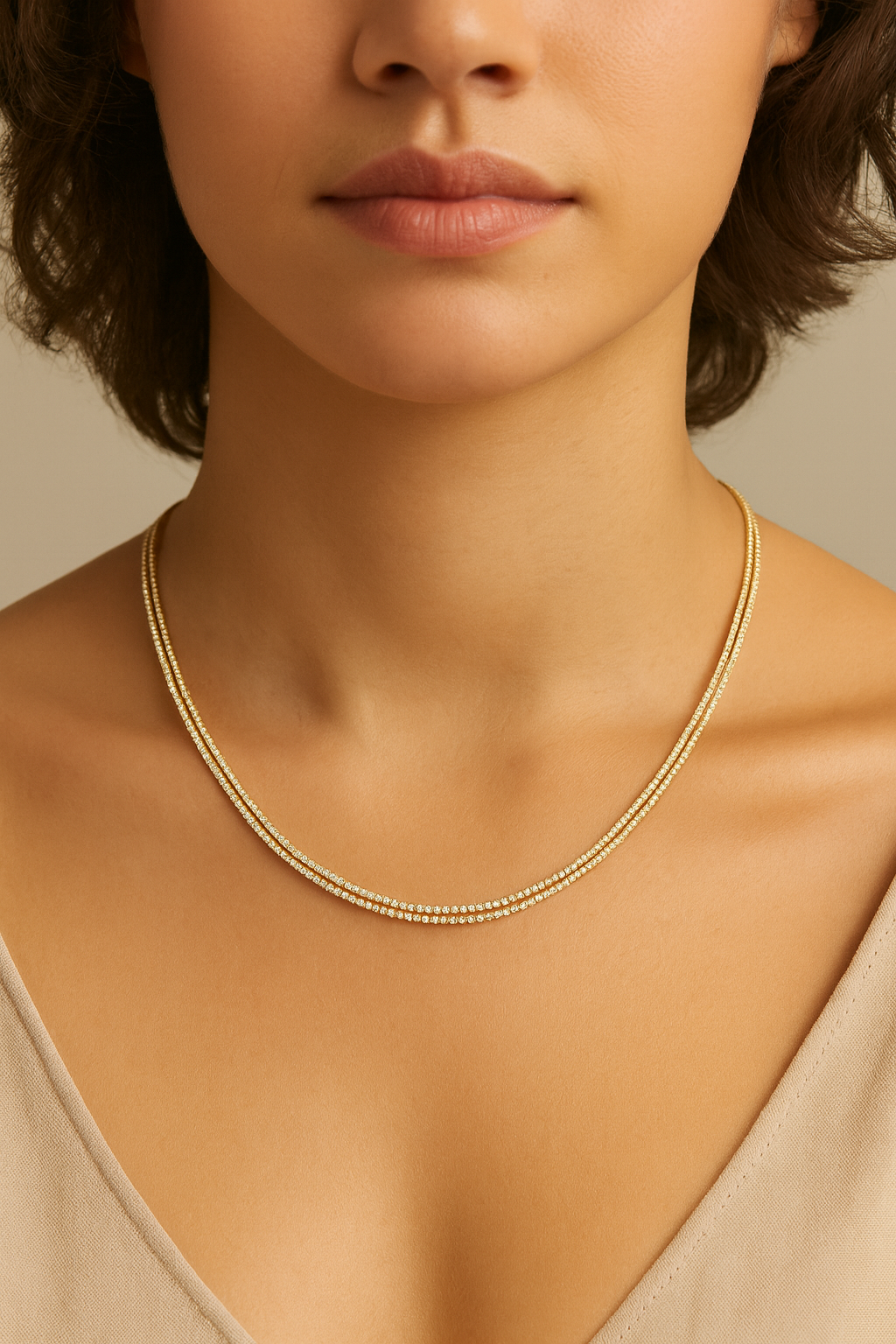 Close-up of a person wearing a gold necklace against a neutral background