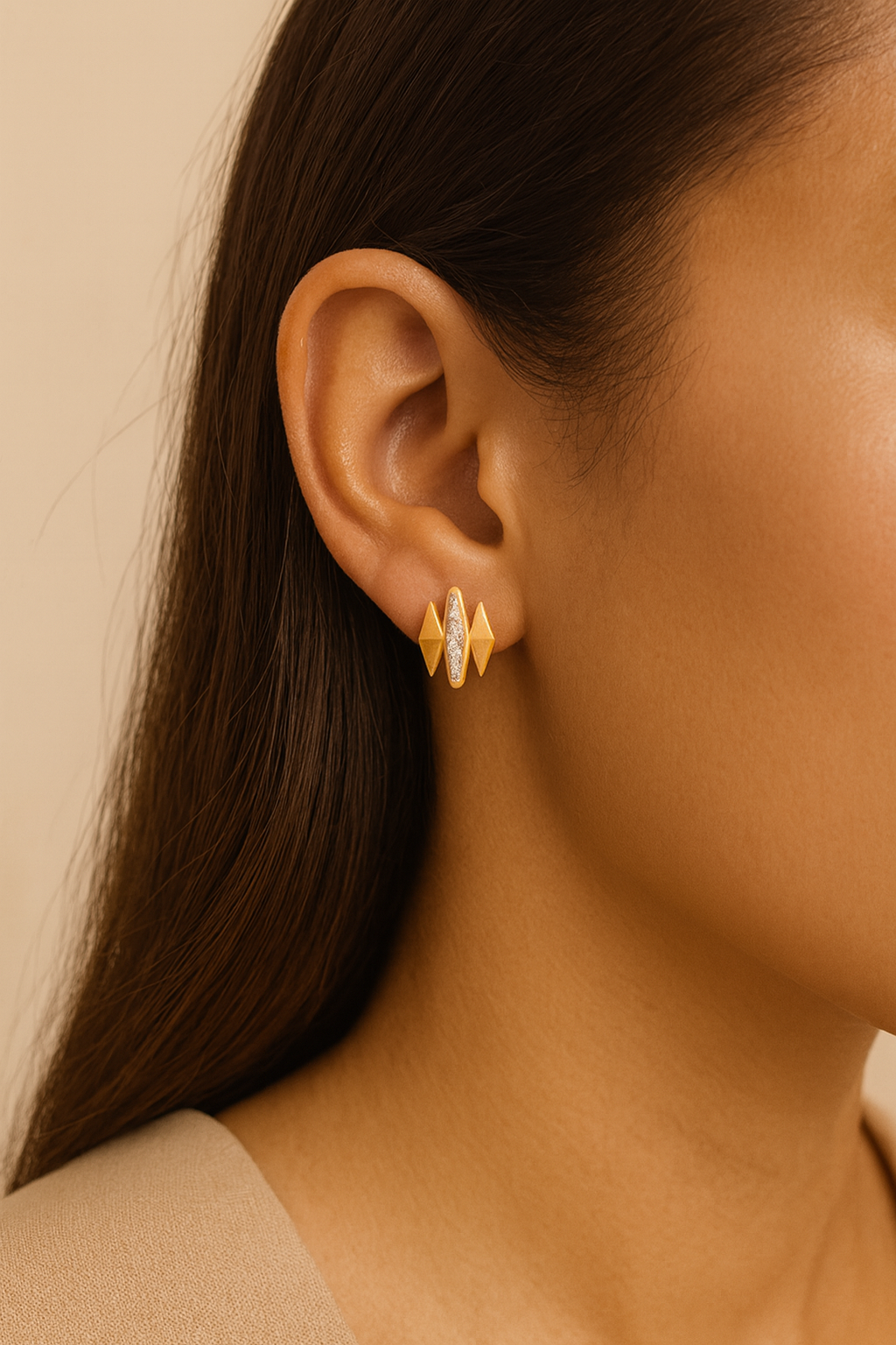 Close-up of a person wearing gold earrings with a neutral background