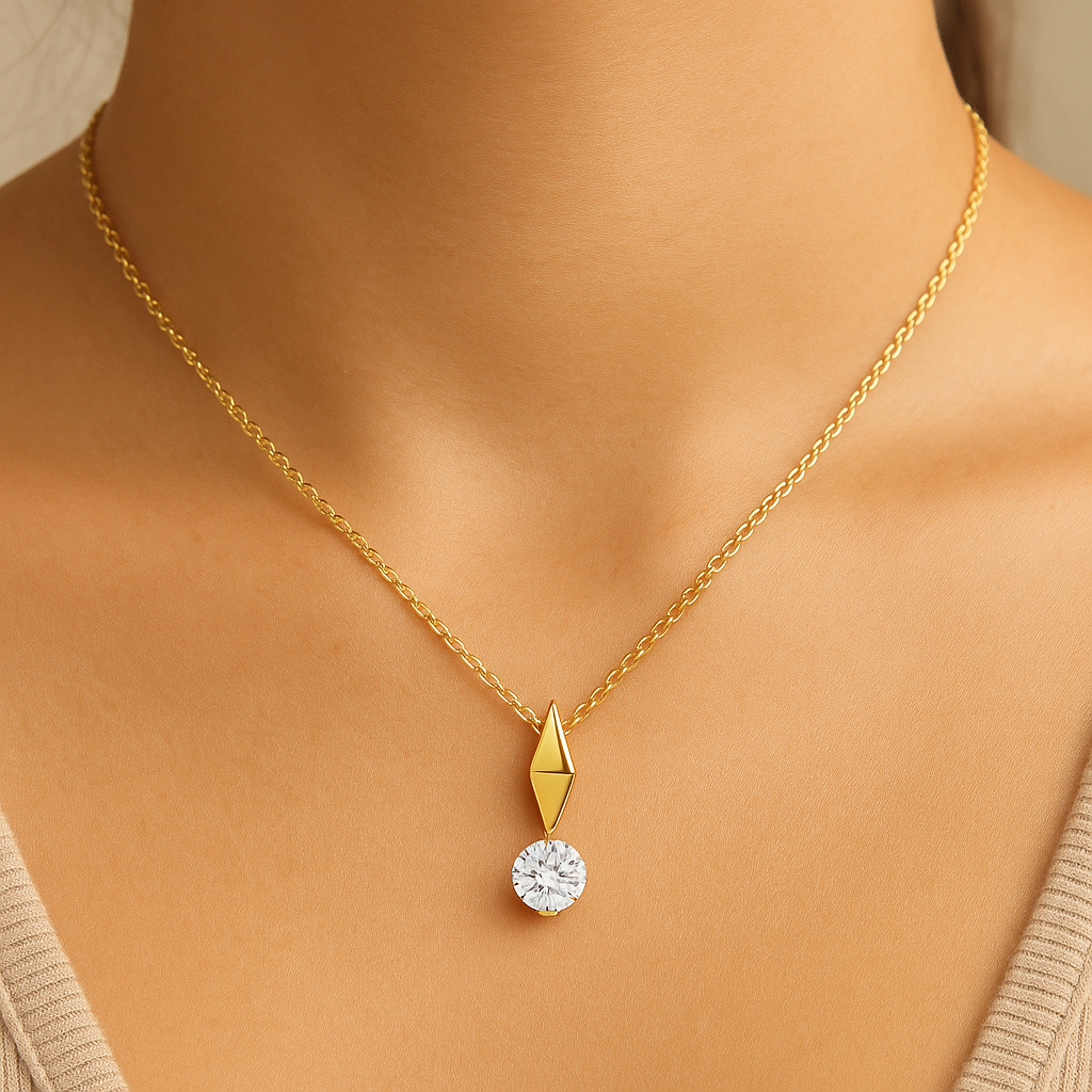 Gold necklace with a diamond pendant on a person wearing a beige top.