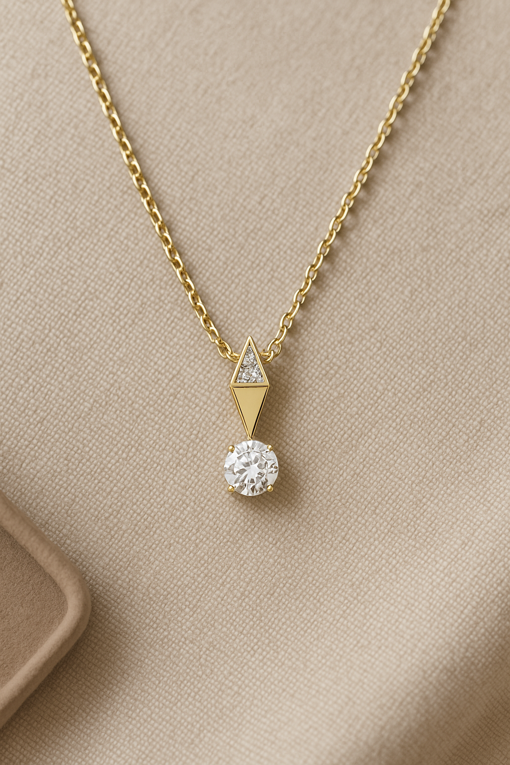 Gold necklace with a diamond pendant on a beige background