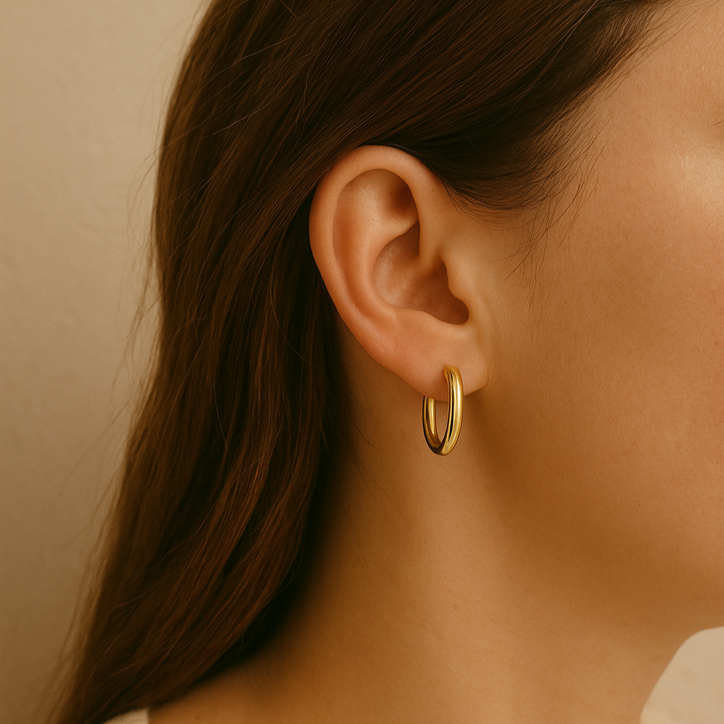 A model wearing gold huggie hoop earrings