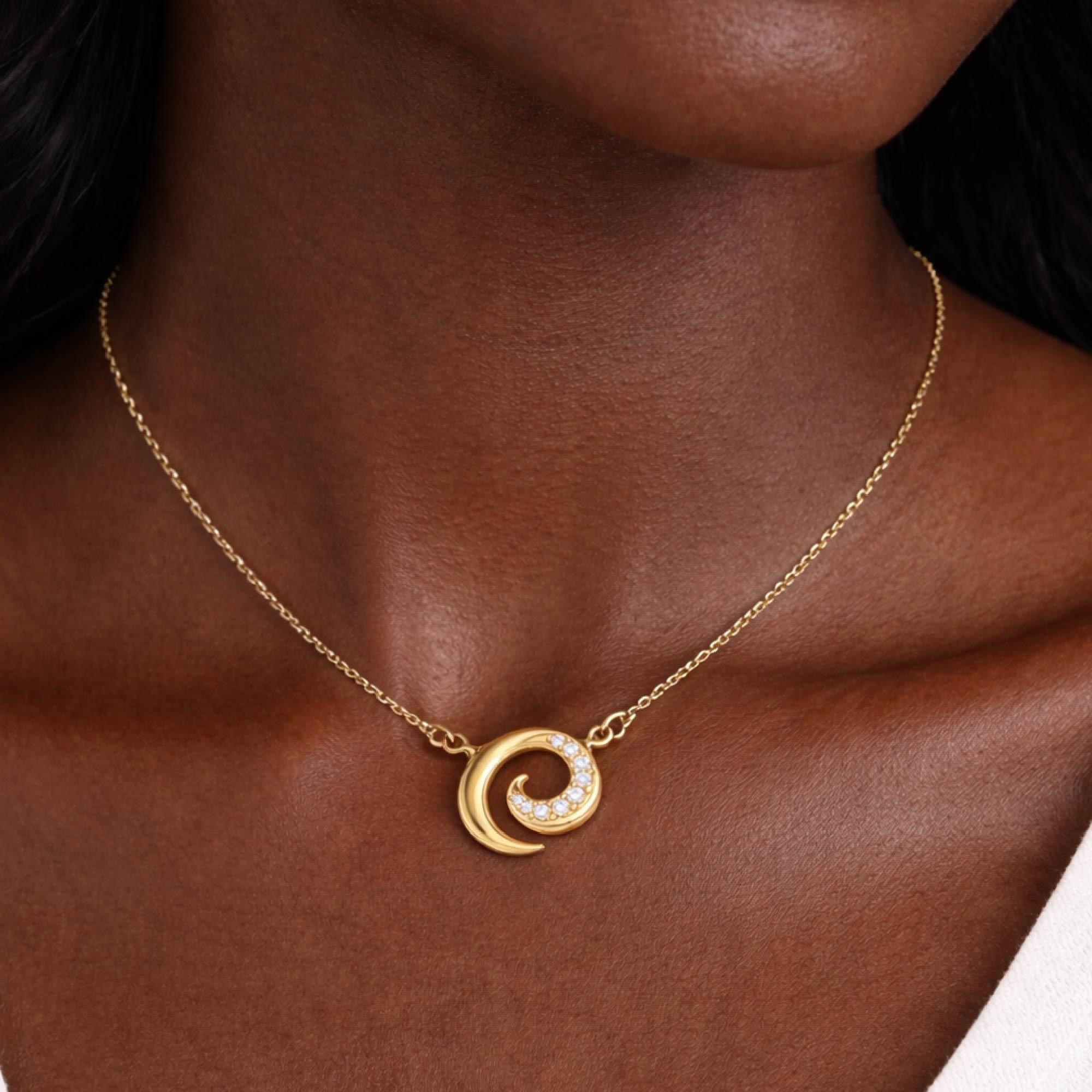 Gold necklace with a crescent moon pendant on a person's neck