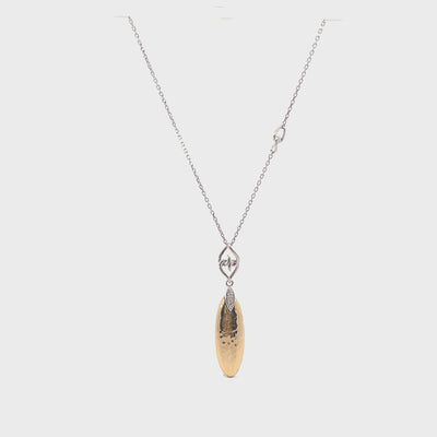 Hammered gold and silver teardrop pendant necklace on white textured surface with flowers.
