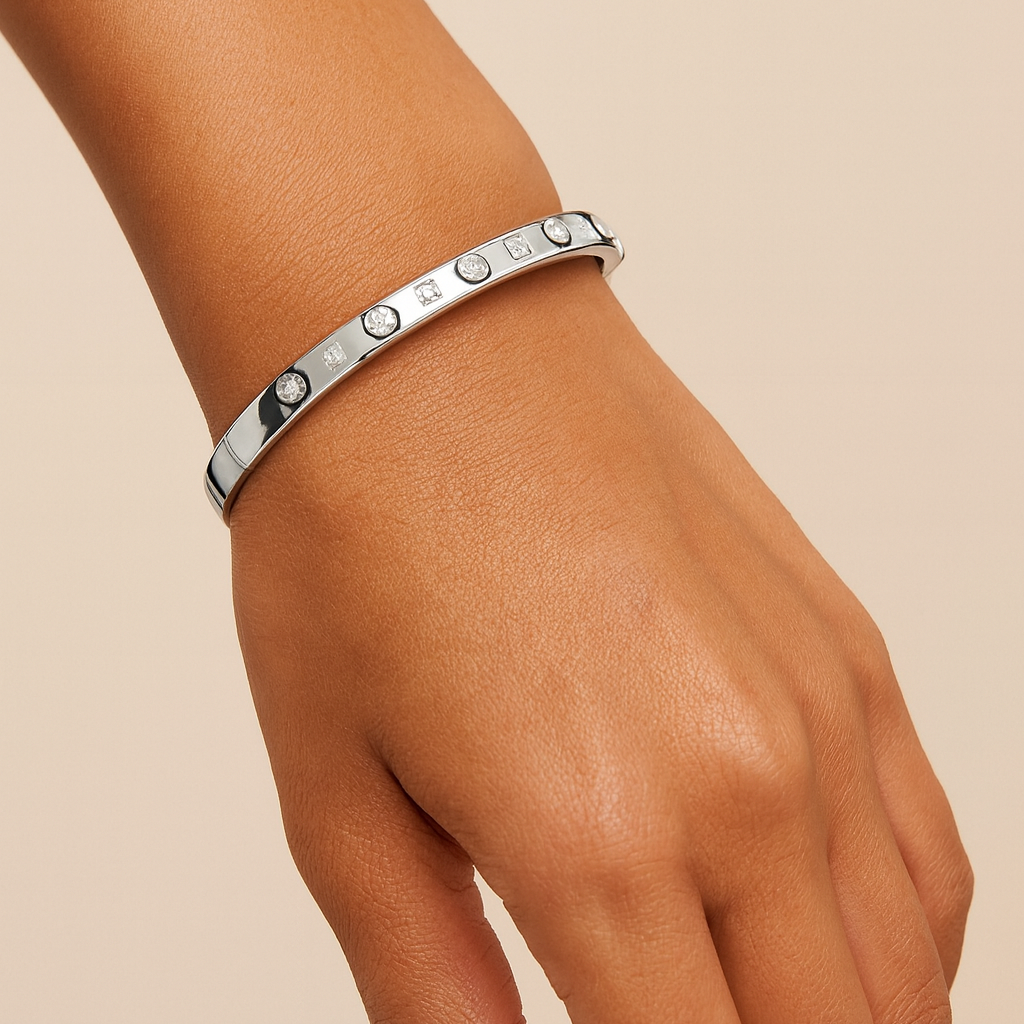 Silver bracelet on a wrist against a beige background