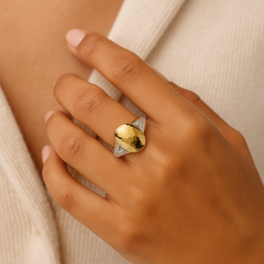 Hand wearing a gold ring with a stone on a neutral background